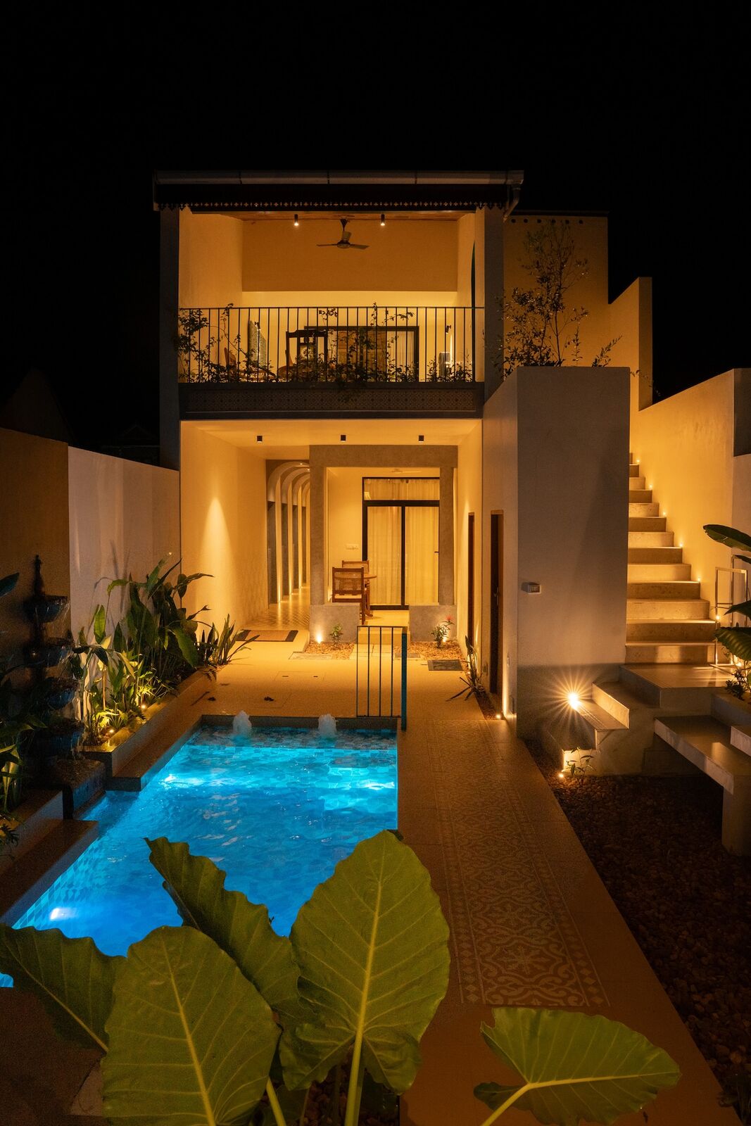 The pool lit at night, the villa's interiors glowing behind it.