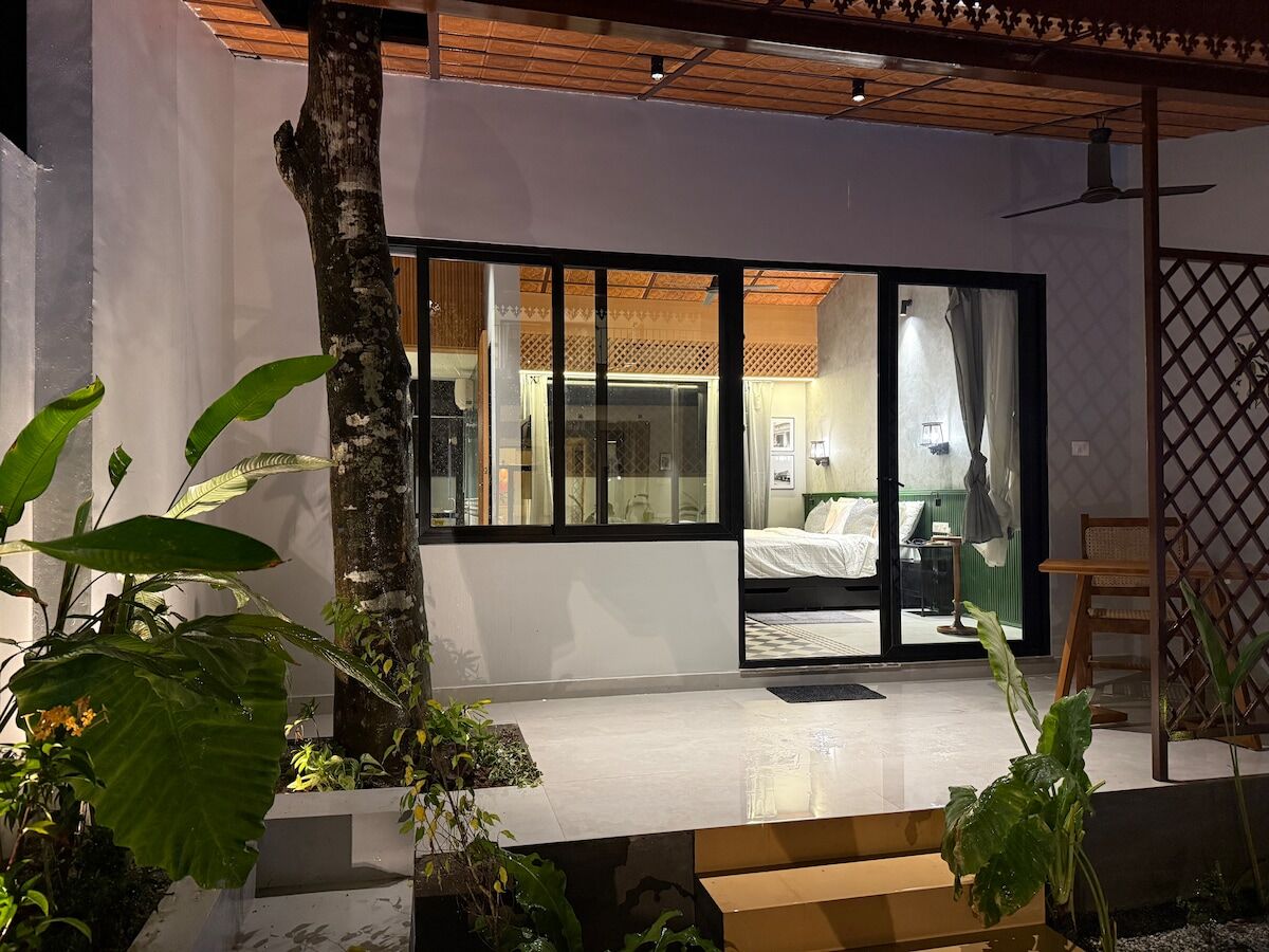 Bedroom three seen from the planted courtyard, its glass doors folded open.